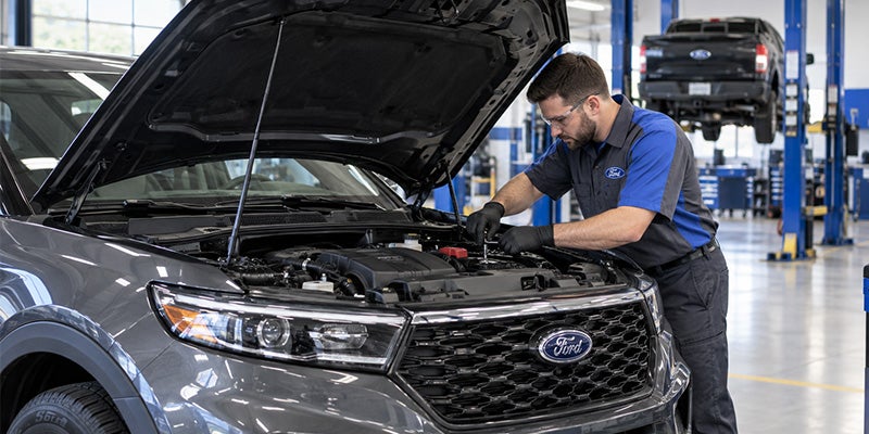 A service technician under the hood of a vehicle in the service center.